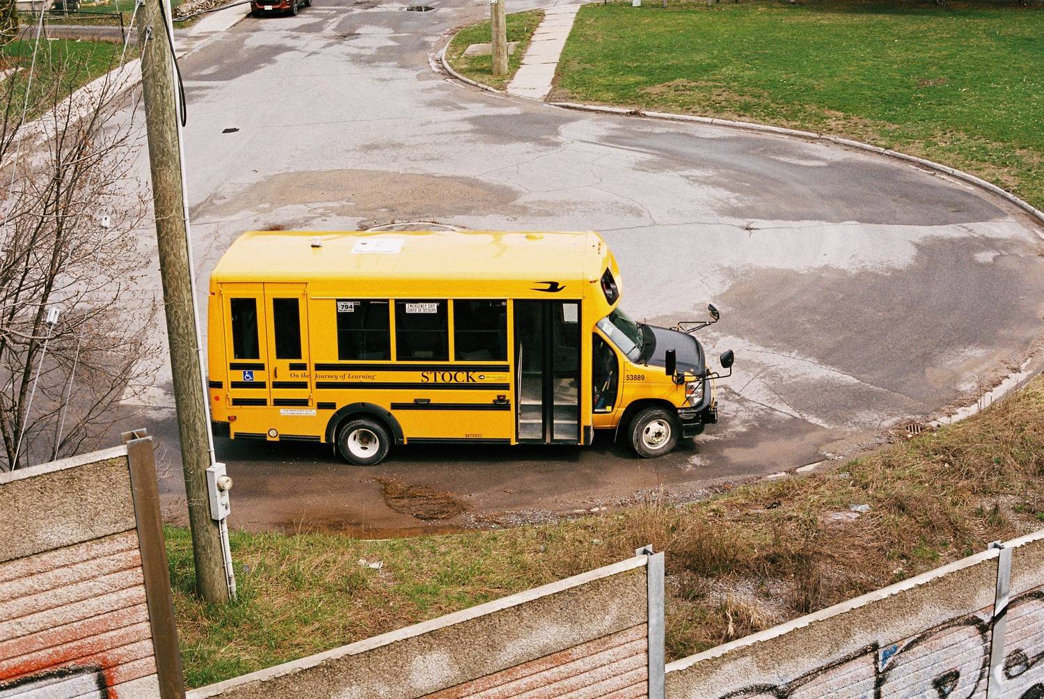 Yellow school bus navigating a newly repaired asphalt drop-off loop at an educational facility.
