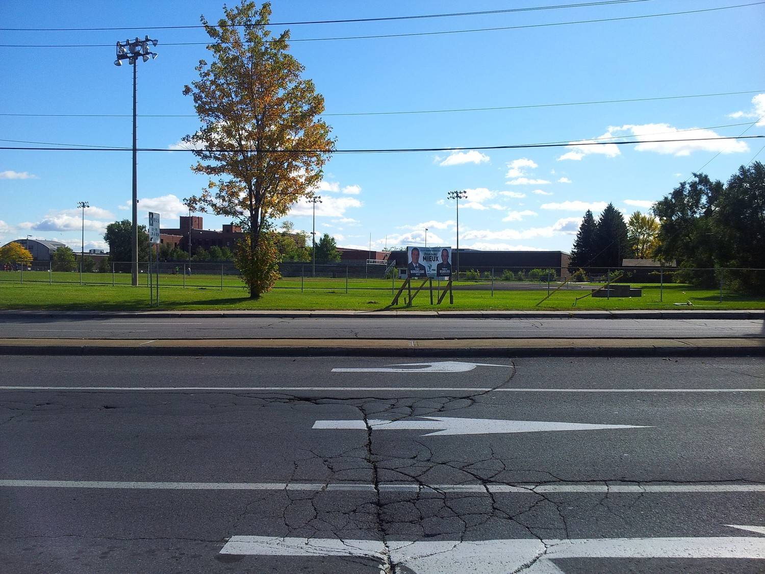 Cracked asphalt road needing maintenance near a school campus before the back-to-school season by Asphalt Services Inc.