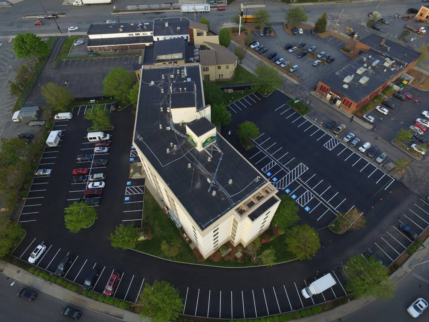 Aerial drone view of a newly paved commercial hotel parking lot with fresh white line striping completed near Peabody MA by Asphalt Services Inc.