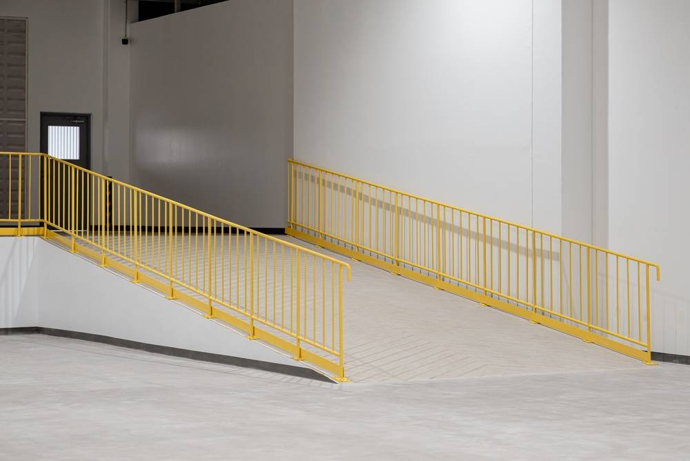 Concrete loading ramp and walkway with safety railings inside a commercial facility, highlighting areas facility managers should inspect before summer traffic peaks and increased loading activity.