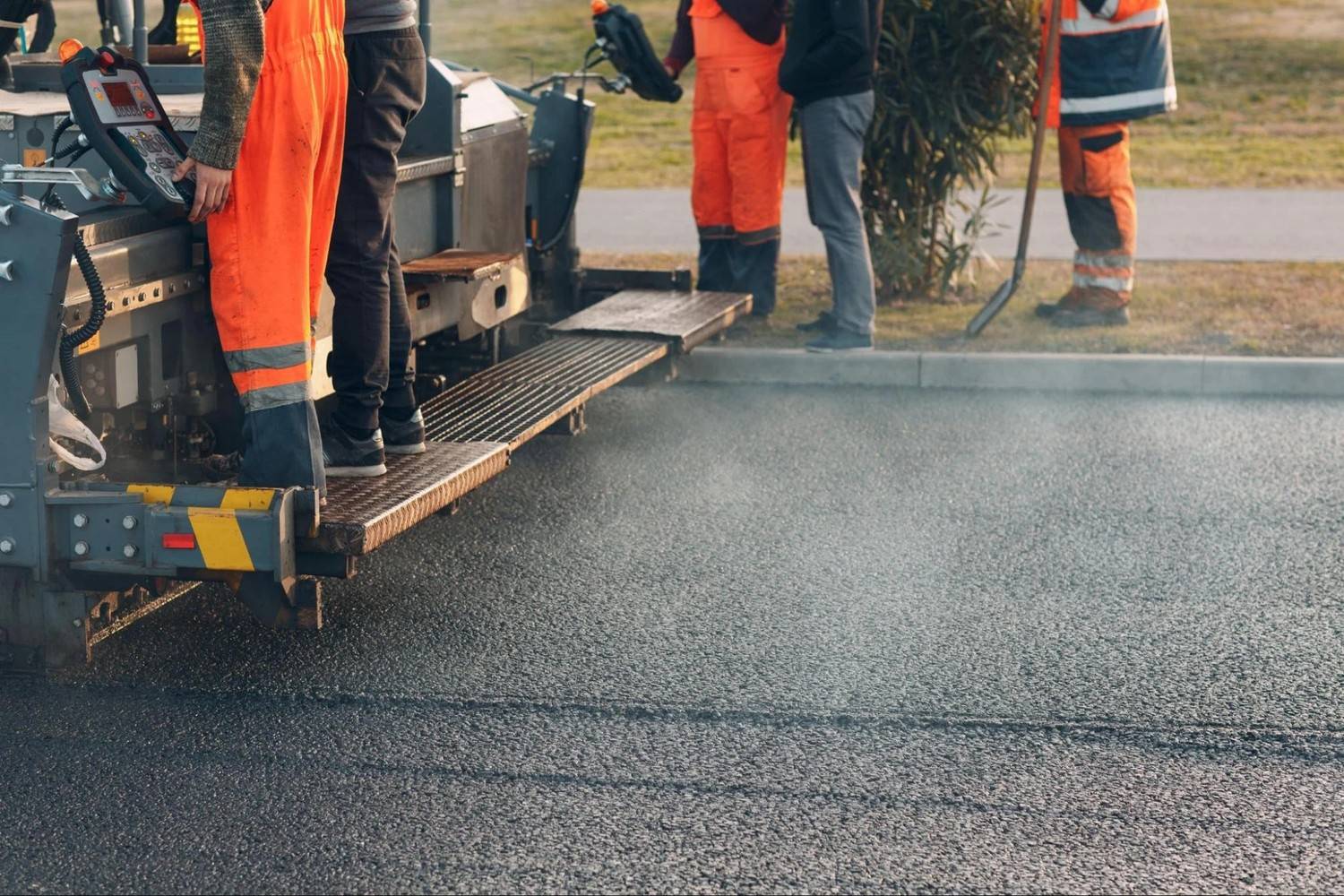 Asphalt Services Inc. crew operating heavy paving equipment to lay fresh asphalt on a commercial roadway project near Boston MA.